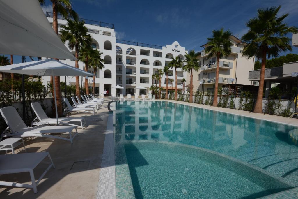 une piscine avec des chaises et un bâtiment dans l'établissement Residence La Villa, à Tortoreto Lido