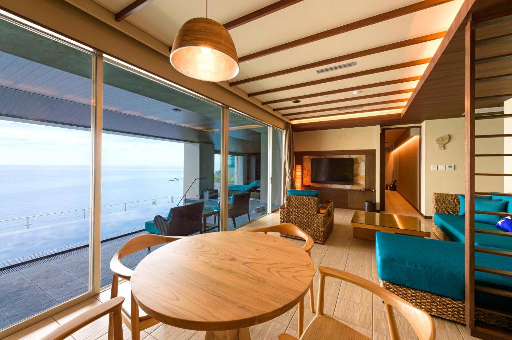 - un salon avec une table, des chaises et une grande fenêtre dans l'établissement AMANE resort SEIKAI, à Beppu