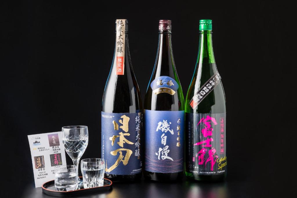 trois bouteilles de vin posées sur une table avec des verres dans l'établissement Izu Mitohama Shotokan, à Numazu