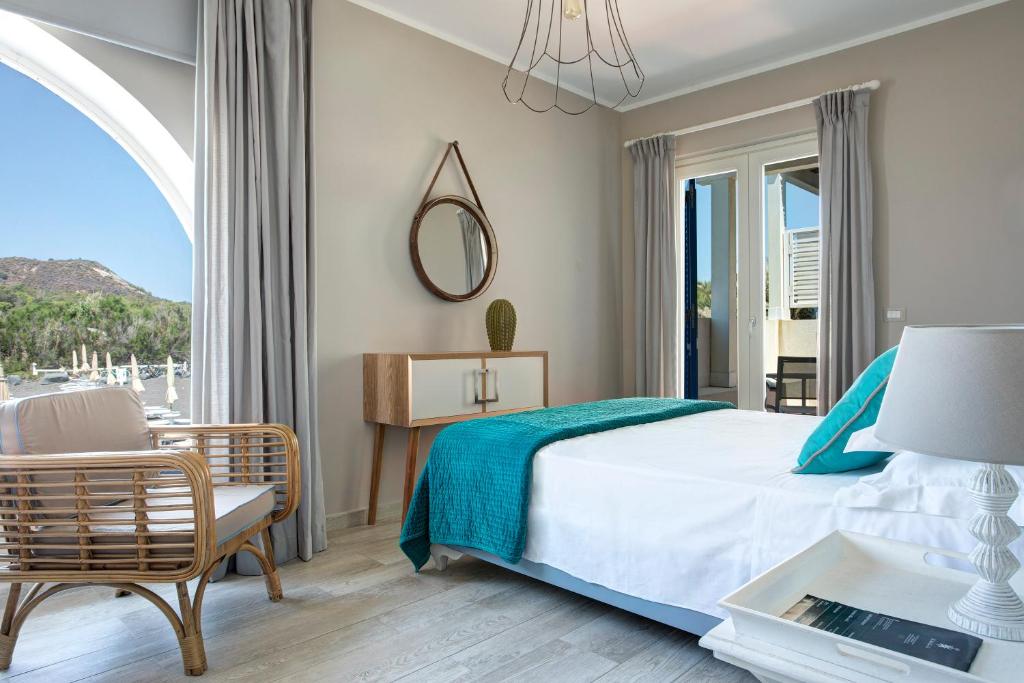 une chambre avec un lit, une table et une chaise dans l'établissement Les Sables Noirs & Spa, à Vulcano