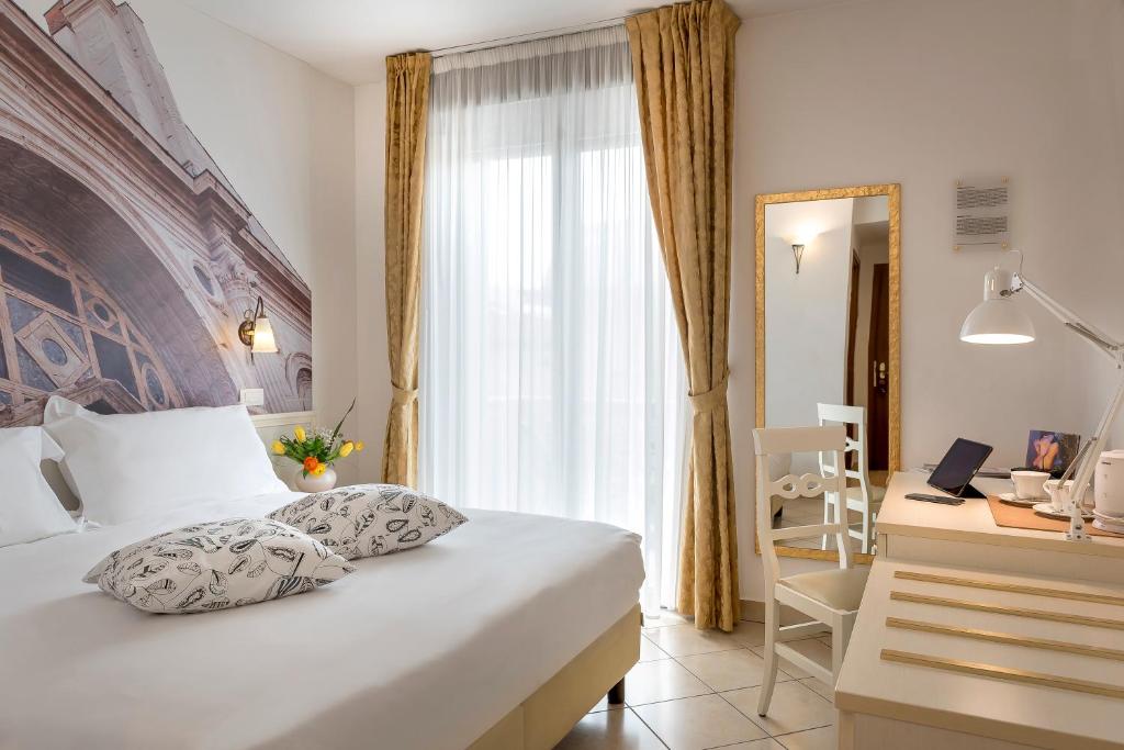 une chambre d'hôtel avec un lit, un bureau et une fenêtre dans l'établissement Sovrana Hotel & SPA, à Rimini