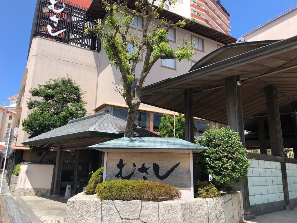 un panneau devant un bâtiment avec un arbre dans l'établissement Musashi, à Shirahama