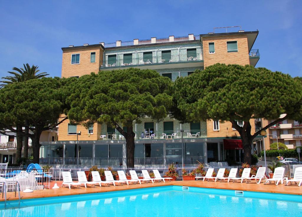 un hôtel avec une piscine bordée de chaises et d'arbres dans l'établissement Hotel Mayola Mhotelsgroup, à San Bartolomeo al Mare