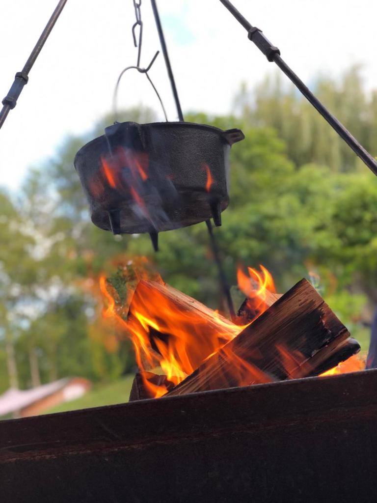 un foyer extérieur avec un pot suspendu à la flamme dans l'établissement Gite colombe des bois, à Estadens