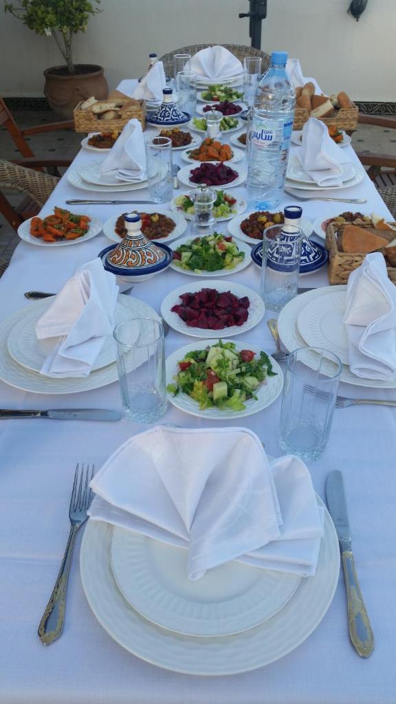 une table blanche avec des assiettes de nourriture dans l'établissement Riad Batchisarai, à Fès