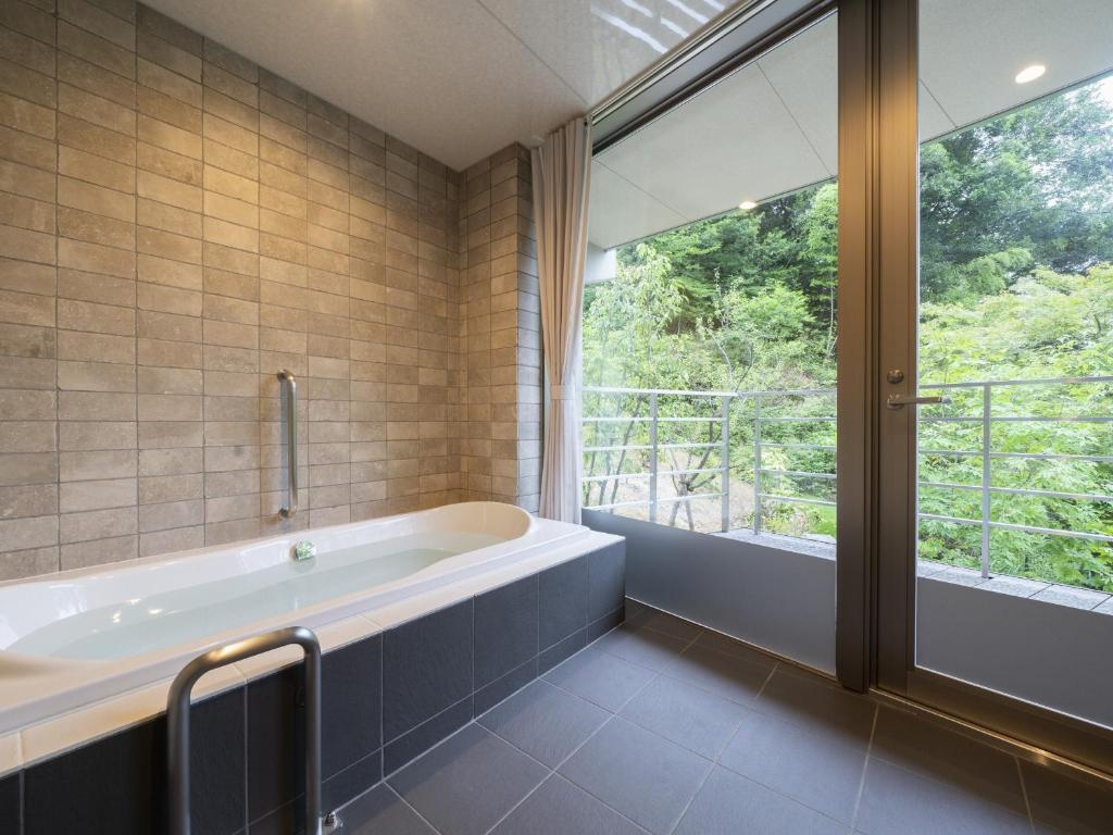une salle de bain avec baignoire et une grande fenêtre dans l'établissement Hotel Sekisuien, à Gujō