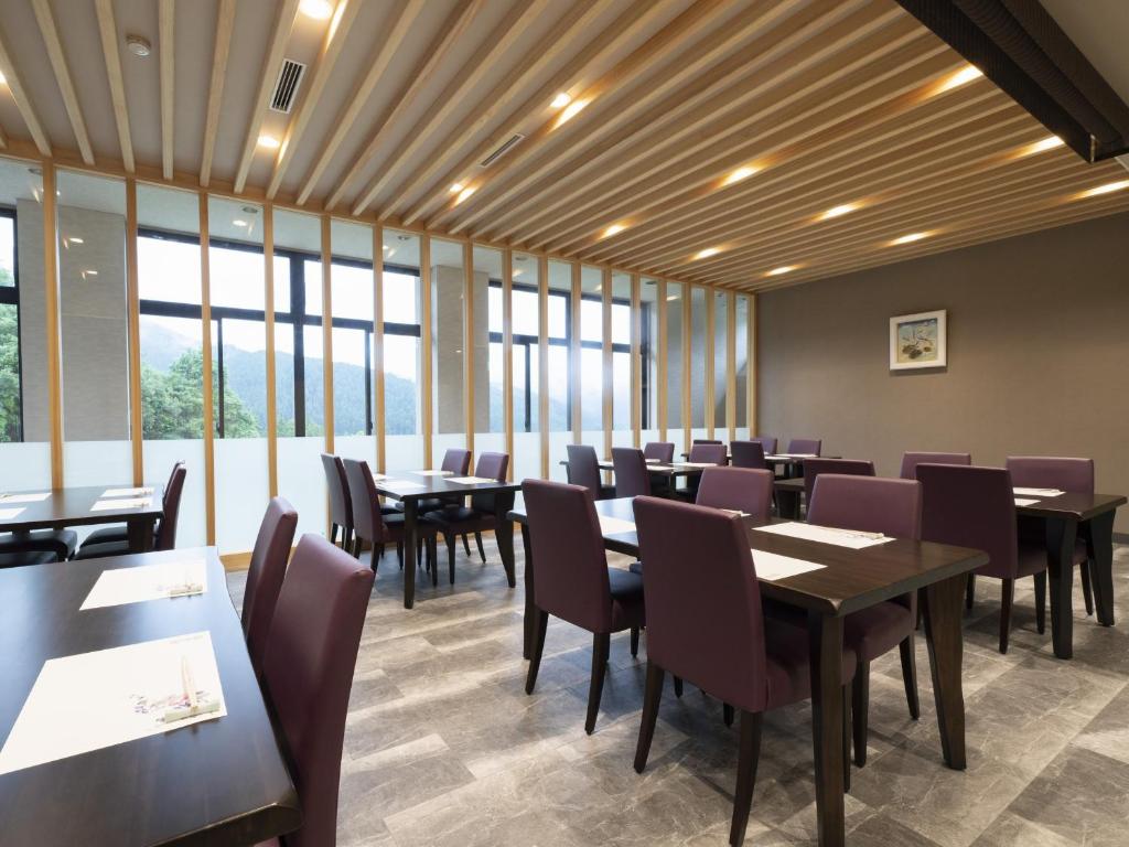 une salle à manger avec tables, chaises et fenêtres dans l'établissement Hotel Sekisuien, à Gujō