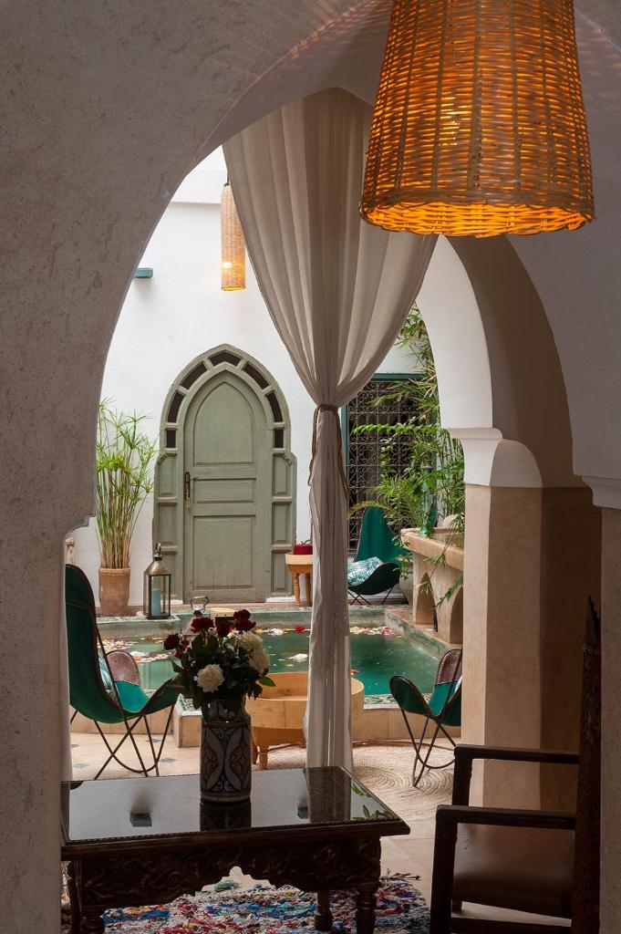 Cette chambre dispose d'une piscine et d'une table avec un vase de fleurs. dans l'établissement Riad la Cle de la Medina, location en exclusivite, à Marrakech