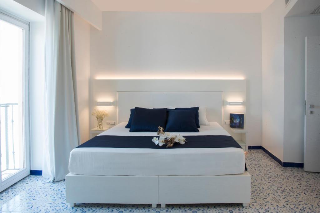une chambre avec un grand lit blanc avec des oreillers bleus dans l'établissement Lloyd's Baia Hotel, à Vietri