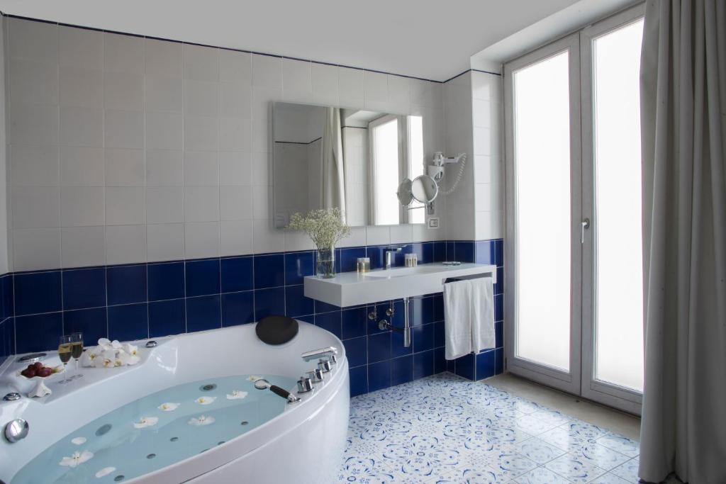 La salle de bains bleue et blanche est pourvue d'une baignoire et d'un lavabo. dans l'établissement Lloyd's Baia Hotel, à Vietri