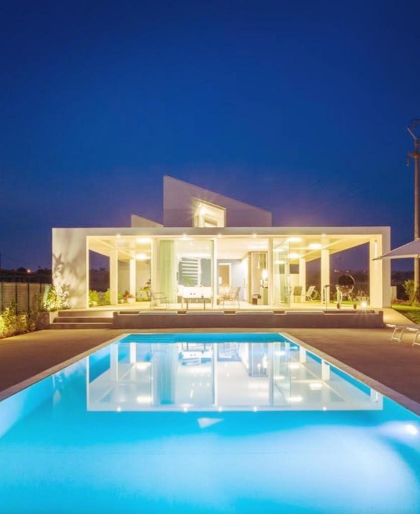 une villa avec une piscine la nuit dans l'établissement Villa Arillà con piscina e padel, à Marina di Ragusa