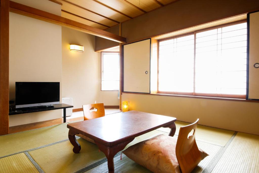 un salon avec une table et une télévision dans l'établissement Osaka Ryokan Kuramoto, à Osaka 10 autres photos