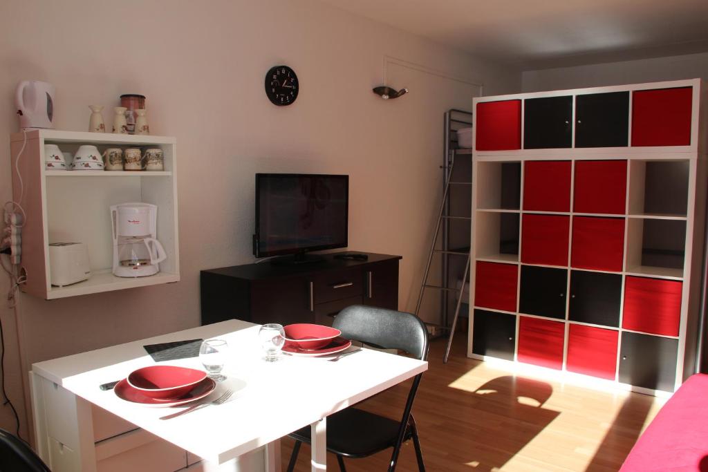 Cette chambre dispose d'une table blanche et d'un mur rouge. dans l'établissement Studio au pied des pistes + Cellier, à La Mongie