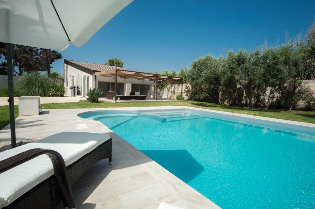 - une piscine avec un parasol et une maison dans l'établissement Villa mare Fontane Bianche, à Fontane Bianche