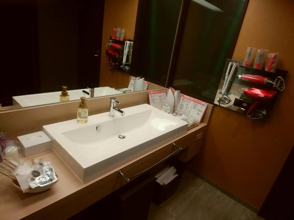 une salle de bain avec un lavabo blanc et un miroir dans l'établissement Hotel PLAISIR (Adult Only), à Hiroshima