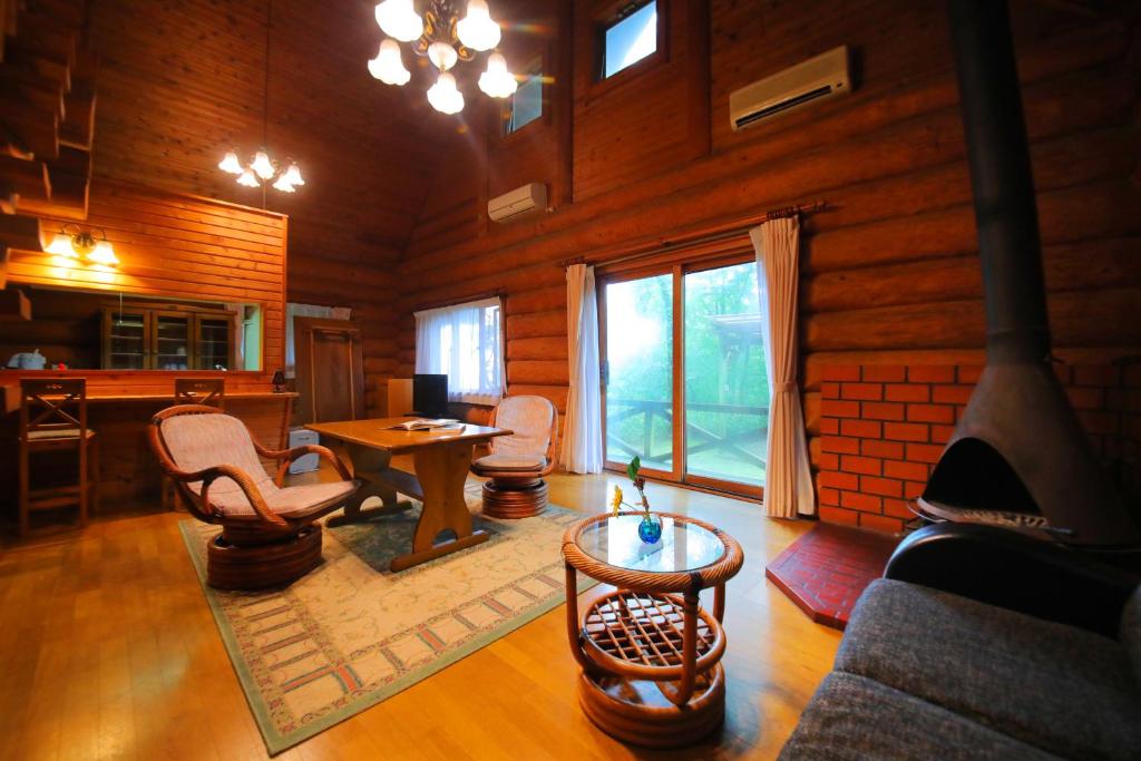 - un salon avec une cheminée, une table et des chaises dans l'établissement Sakura Sakura Onsen, à Kirishima