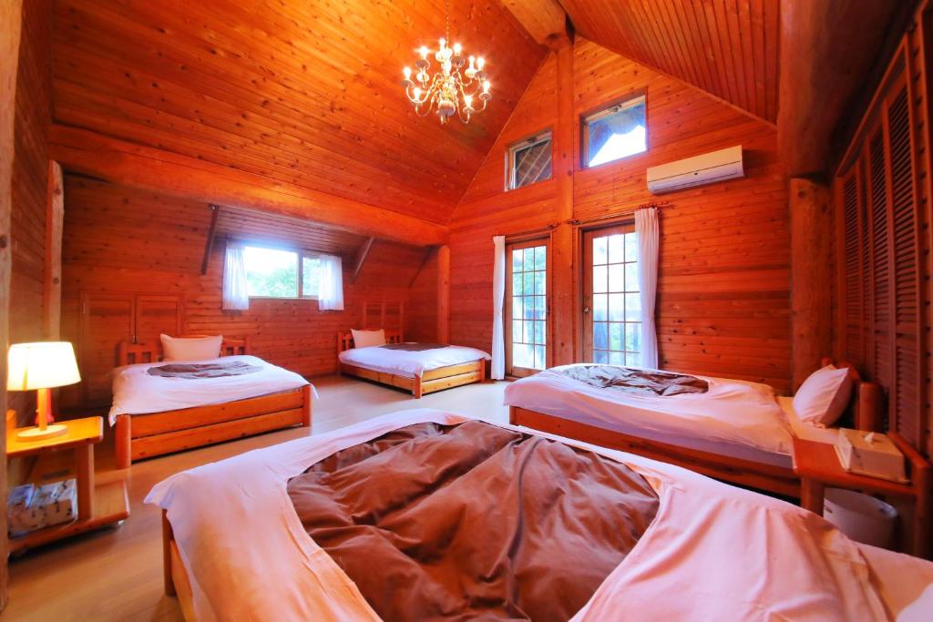 - une chambre avec 3 lits dans une cabane en bois dans l'établissement Sakura Sakura Onsen, à Kirishima