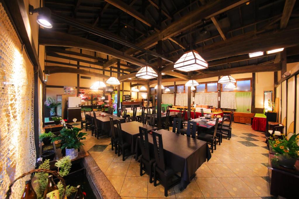 une salle à manger avec des tables et des chaises dans un restaurant dans l'établissement Sakura Sakura Onsen, à Kirishima