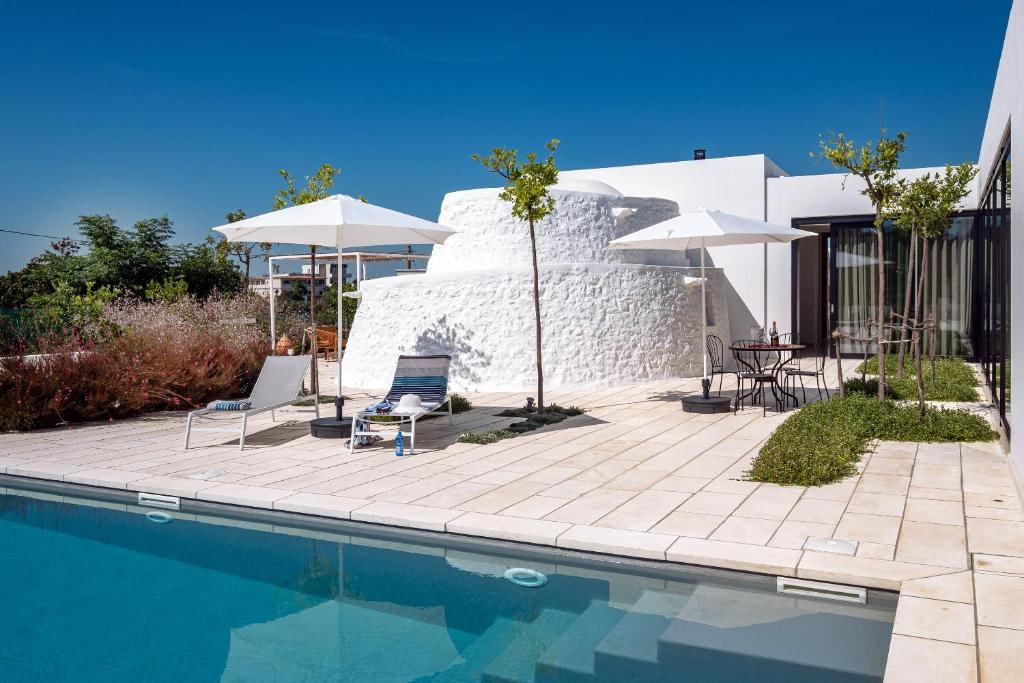 - une piscine avec des chaises et des parasols à côté d'une maison dans l'établissement Villa ELGAR, à Ostuni
