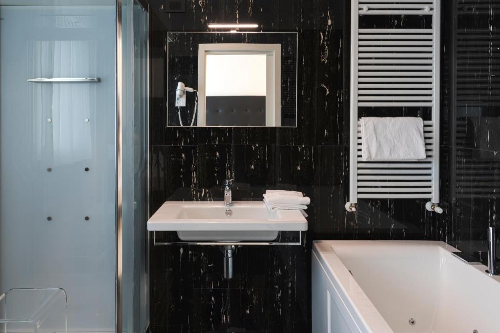 une salle de bain avec un lavabo, une baignoire et un miroir dans l'établissement Hotel Villa Corallo, à San Benedetto del Tronto