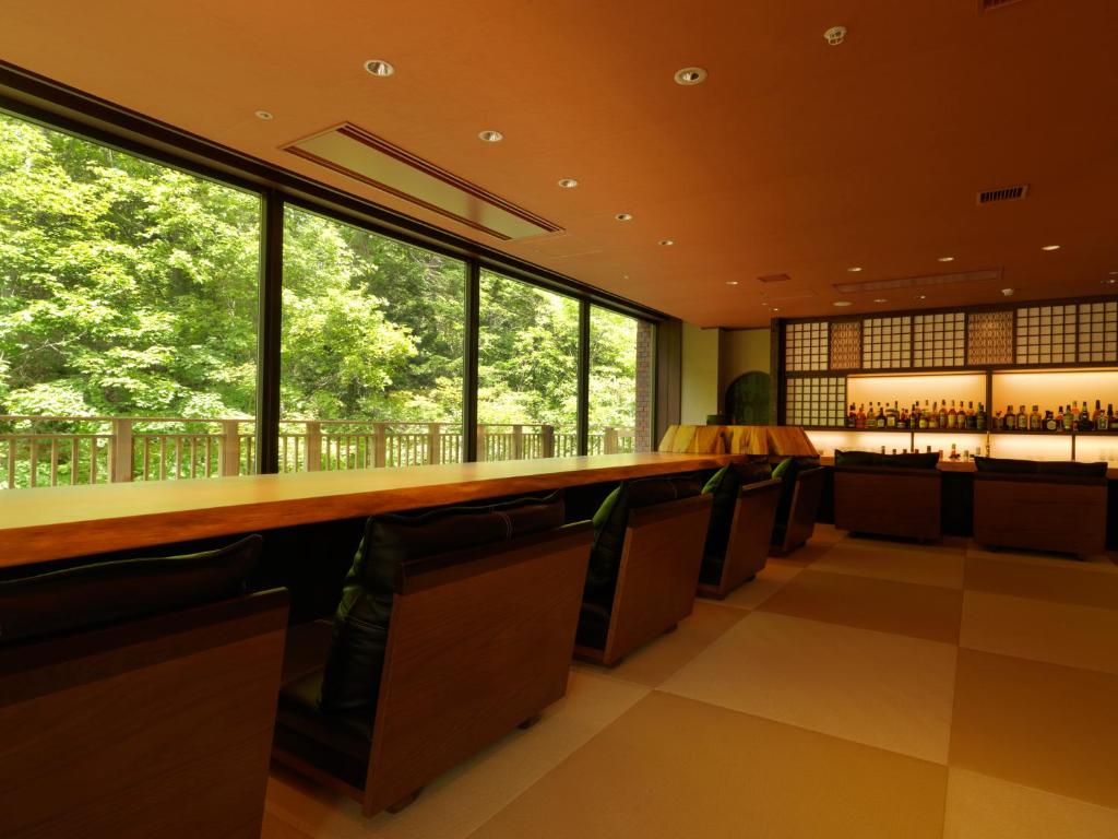 - un bar avec des chaises, un long comptoir et des fenêtres dans l'établissement Niseko Konbu Onsen Tsuruga Moku-no-sho, à Niseko