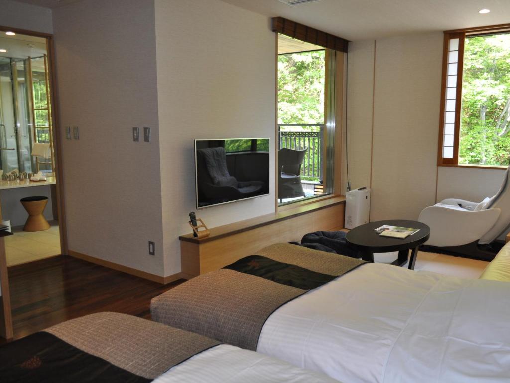 une chambre d'hôtel avec deux lits et une télévision dans l'établissement Niseko Konbu Onsen Tsuruga Moku-no-sho, à Niseko