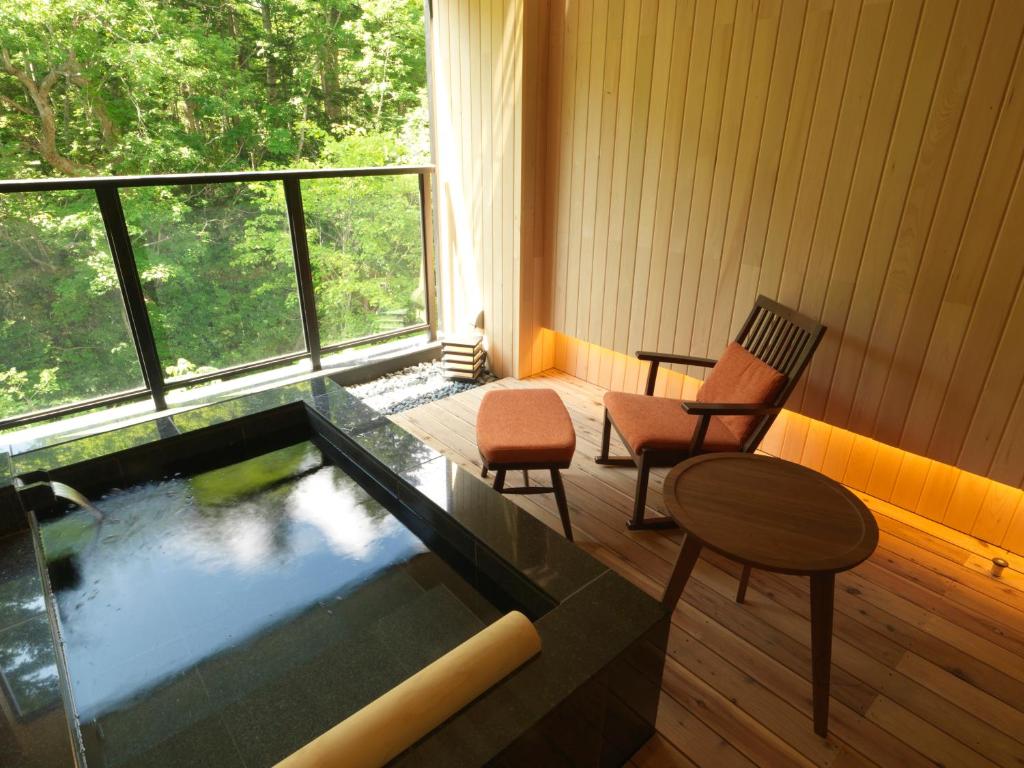 Cette chambre comprend une baignoire avec deux chaises et une table. dans l'établissement Niseko Konbu Onsen Tsuruga Moku-no-sho, à Niseko