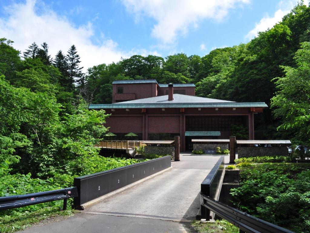 un bâtiment au milieu d'une route avec un pont dans l'établissement Niseko Konbu Onsen Tsuruga Moku-no-sho, à Niseko