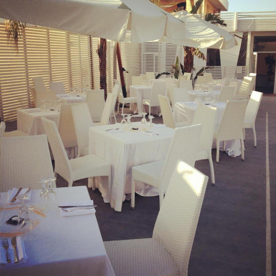 un restaurant avec des tables blanches, des chaises blanches et des parasols dans l'établissement Hotel La Terrazza, à Barletta