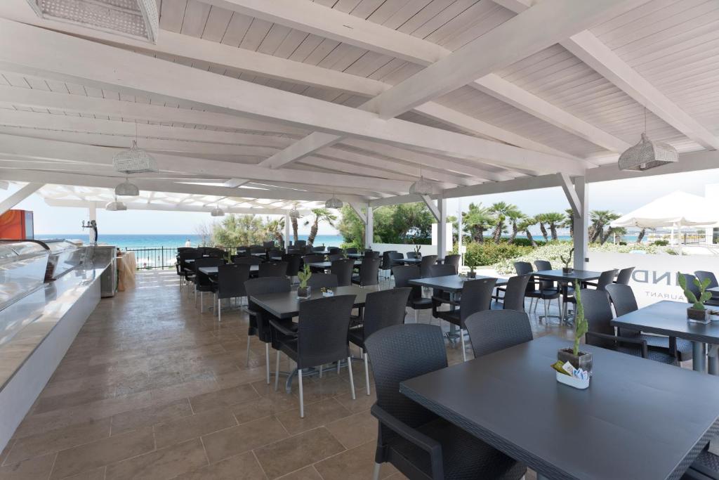 un restaurant avec des tables et des chaises noires et l'océan dans l'établissement Grand Hotel Costa Brada, à Gallipoli