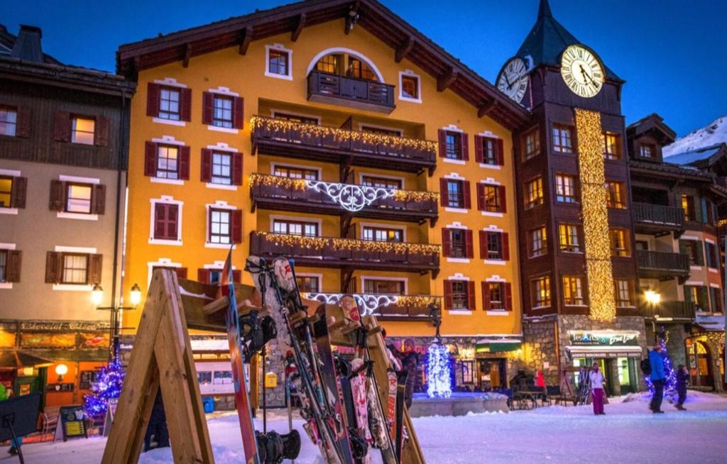 un bâtiment avec une tour d'horloge et des skis en face de celle-ci dans l'établissement Arc1950 Prince Des Cimes appt 4-5 pers ski in out piscine intérieure, à Arc 1950