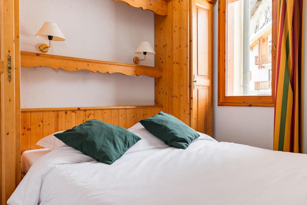 une chambre avec un lit avec deux oreillers verts dans l'établissement travelski home select - Résidence Les Chalets du Galibier, à Valloire 9 autres photos