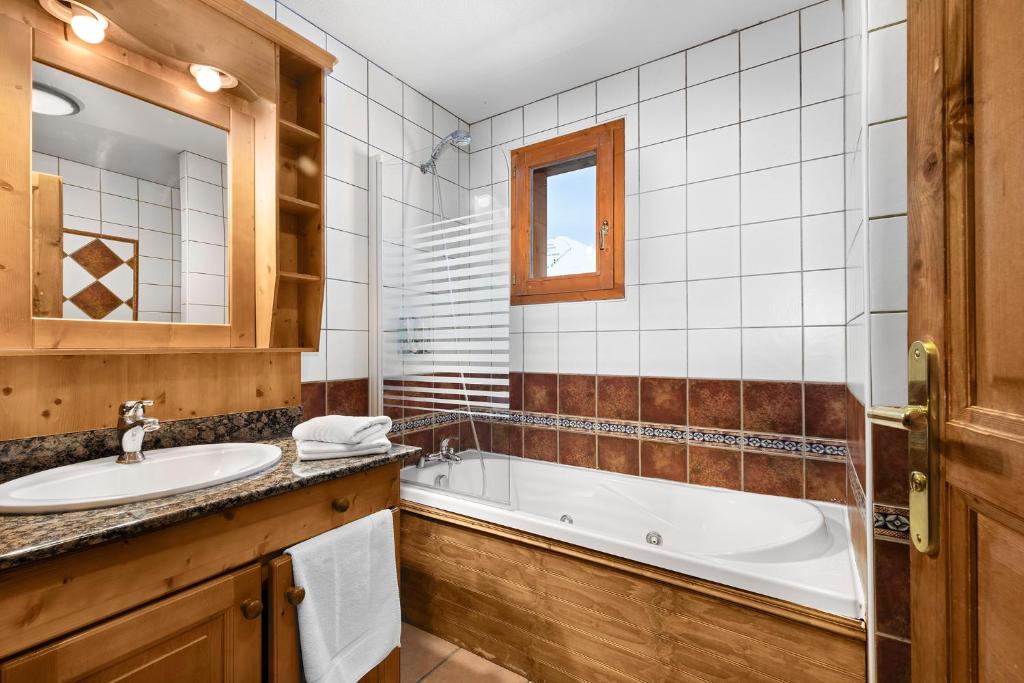 une salle de bain avec une baignoire et un lavabo dans l'établissement Hôtel Les Balcons Village, à Belle Plagne