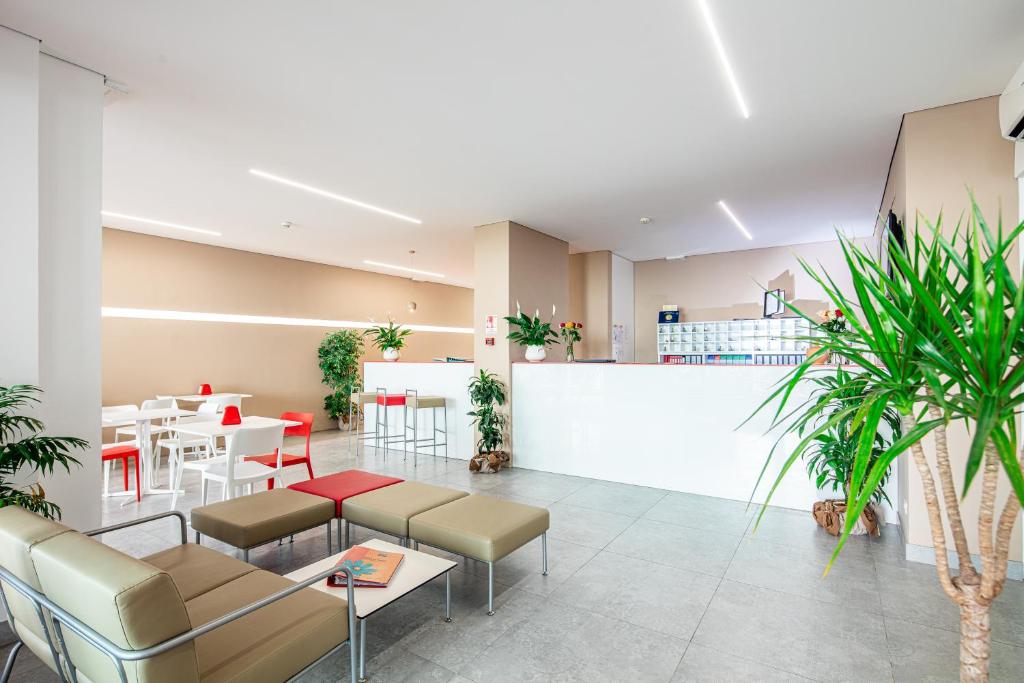 un hall d'entrée avec des chaises et des tables et un bar dans l'établissement Hotel Regina, à Lignano Sabbiadoro