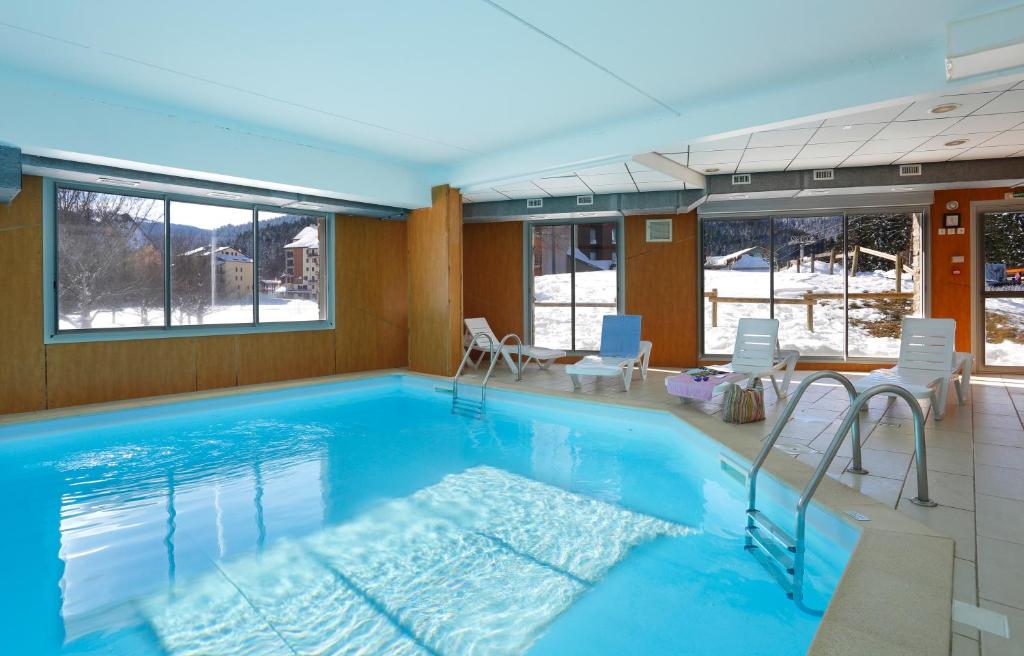 - une grande piscine avec des chaises dans la chambre dans l'établissement Résidence Néméa Les Balcons d'Ax, à Ax-les-Thermes