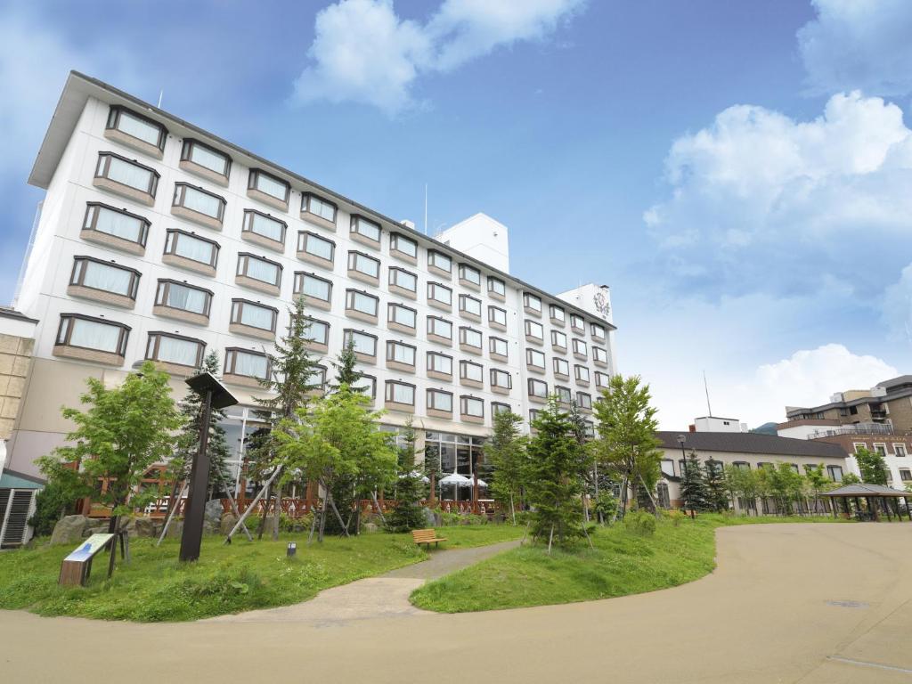 - un grand bâtiment blanc avec un parc en face dans l'établissement THE FOREST AKAN Tsuruga Resort, à Akankohan