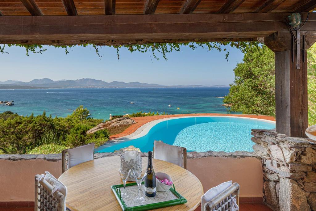 - une table extérieure avec vue sur la piscine dans l'établissement Villa Romantica, à Olbia