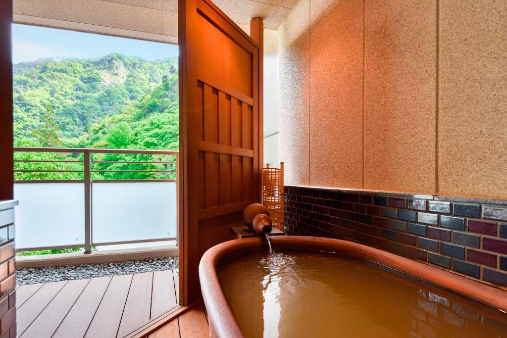 La salle de bains est pourvue d'une baignoire et offre une vue sur la montagne. dans l'établissement Okuno Hosomichi, à Kobe