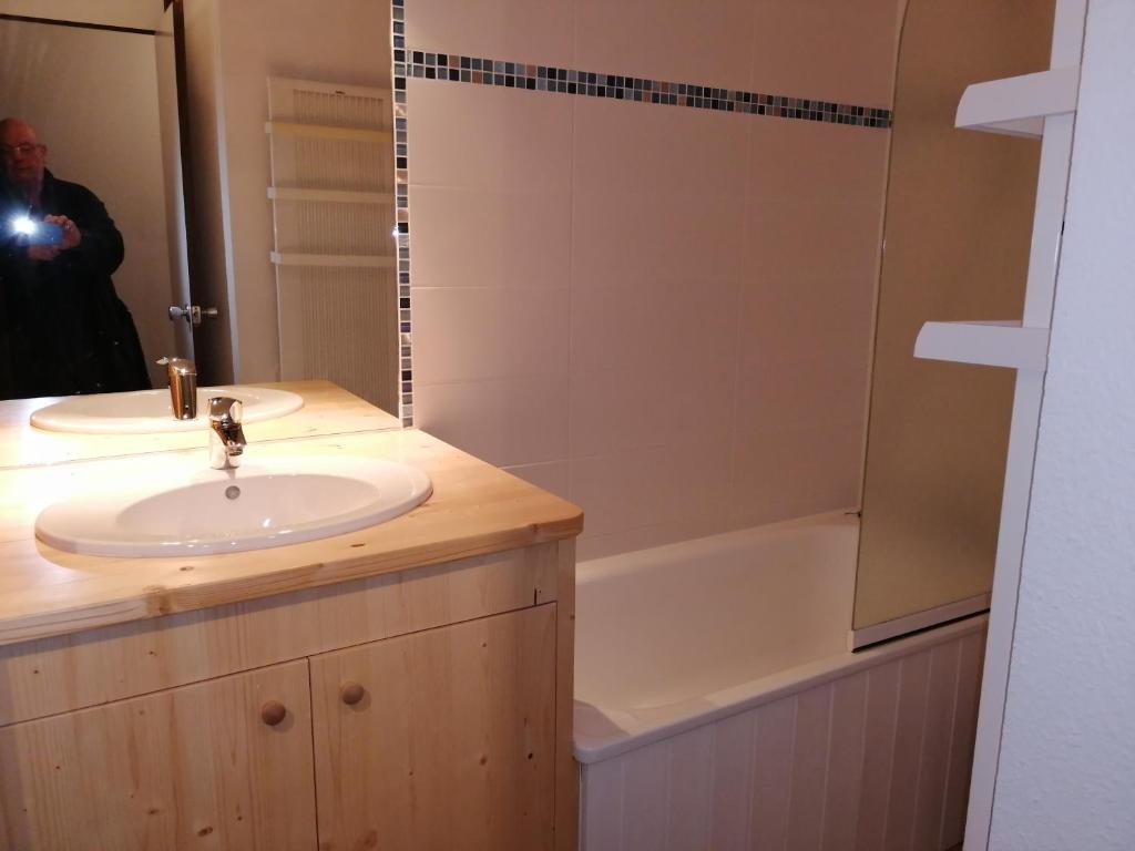 un homme prenant une photo d'une salle de bains avec un lavabo et une baignoire dans l'établissement Plagne AIME 2000 Ski Apartments, à Aime La Plagne 31 autres photos