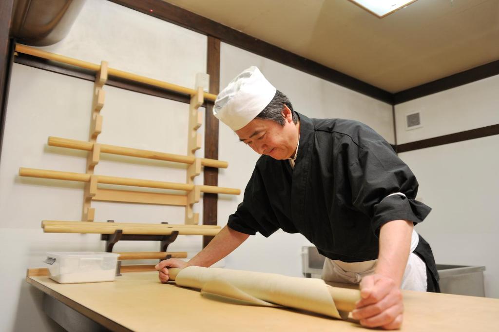 Un homme dans une cuisine qui fabrique une pâte dans l'établissement Izumiya Zenbe, à Matsumoto 37 autres photos