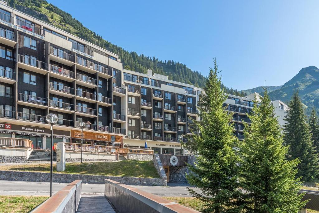 un grand immeuble d'appartements avec des arbres devant lui dans l'établissement Résidence Pierre & Vacances La Forêt, à Flaine