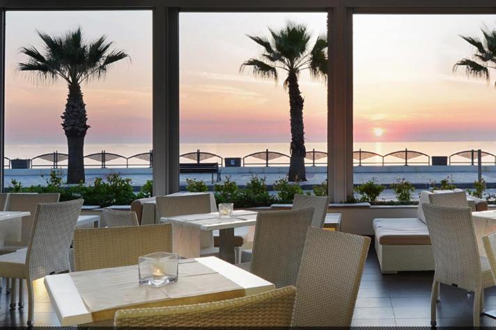 un restaurant avec des tables, des chaises et des palmiers dans l'établissement Hotel Serenella, à Agropoli