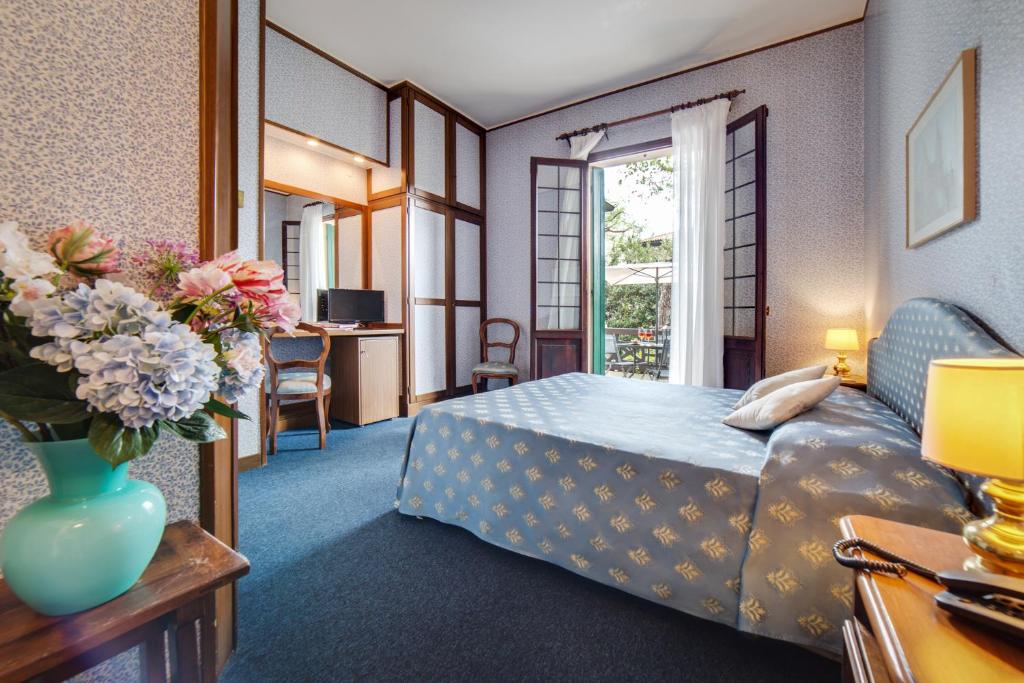 une chambre d'hôtel avec un lit et un vase de fleurs dans l'établissement Hotel La Meridiana, sur le Lido de Venise