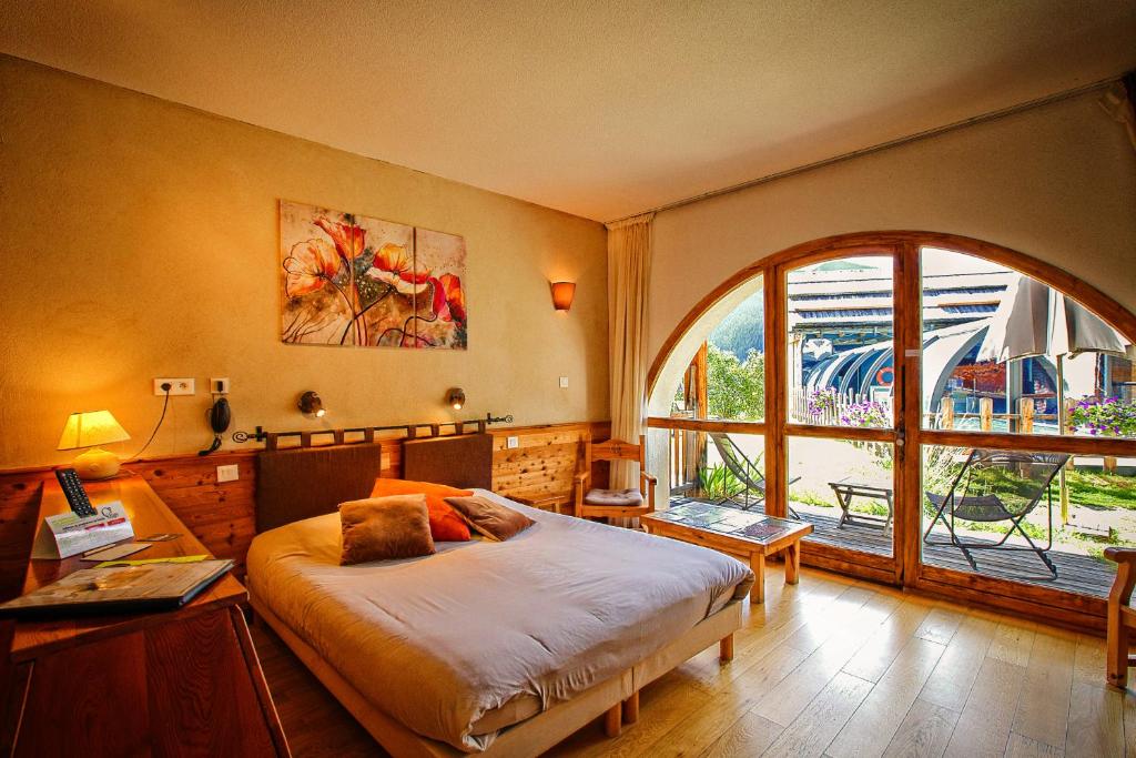 une chambre avec un lit et une grande fenêtre dans l'établissement Hôtel & Spa La Ferme de l'Izoard, à Arvieux