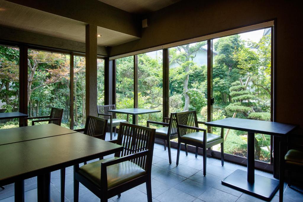 un restaurant avec des tables et des chaises et une grande fenêtre dans l'établissement Ryokan Yoshidaya, à Ureshino