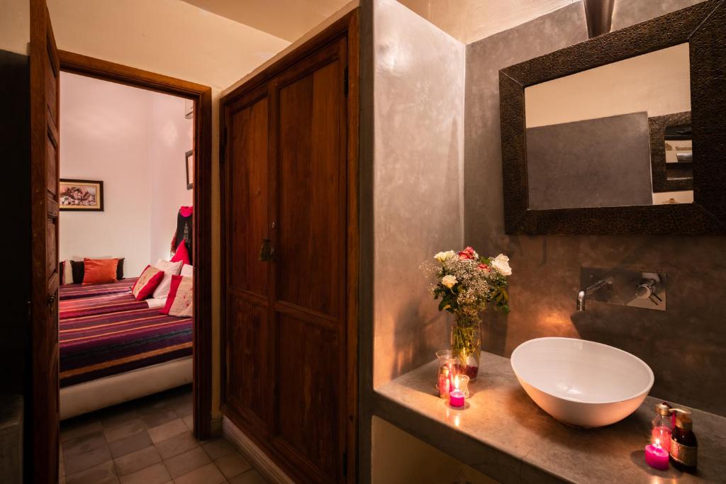 La salle de bains est pourvue d'un lavabo et d'un vase de fleurs sur un comptoir. dans l'établissement Riad Azcona, à Marrakech