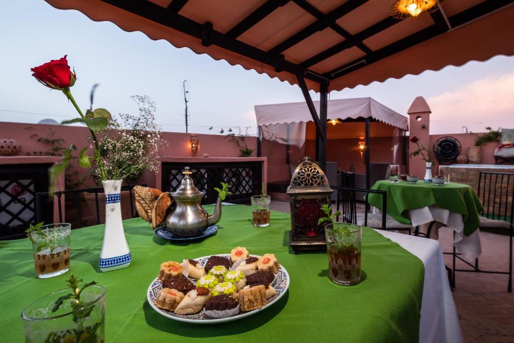 une table avec une assiette de nourriture sur un tissu de table vert dans l'établissement Riad Azcona, à Marrakech
