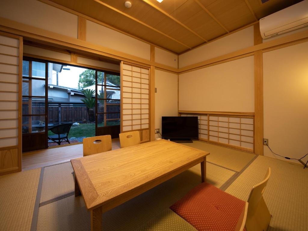 Cette chambre dispose d'une table en bois et d'une grande fenêtre. dans l'établissement 内子の宿 久, à Uchiko