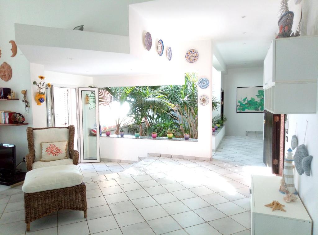 un salon avec une chaise et une grande fenêtre dans l'établissement Villa Luce, à Syracuse