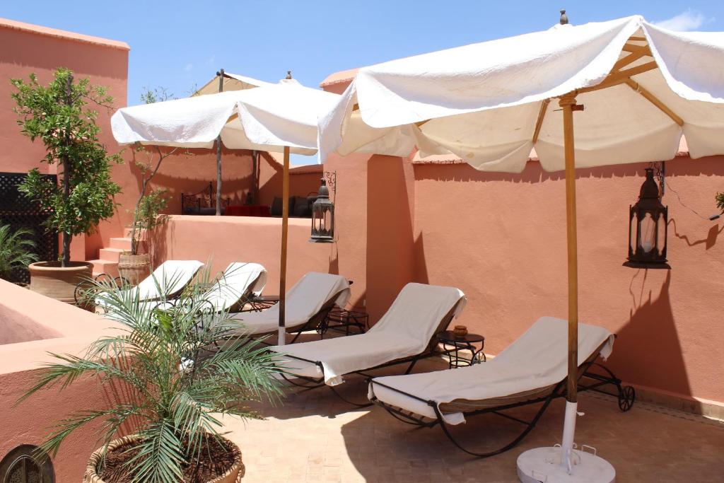 - un ensemble de chaises et de parasols sur une terrasse dans l'établissement Riad Smara, à Marrakech